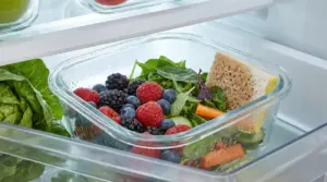 Contenitore con frutta, verdura e una spugnetta all'interno di un frigorifero