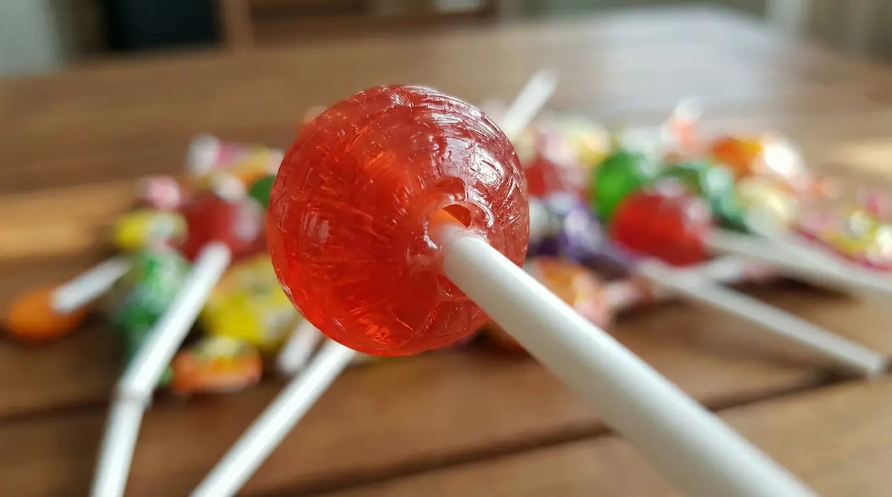 Primo piano di un lecca-lecca rosso con foro visibile sul bastoncino.