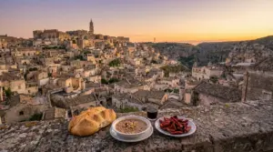 Panorama dei Sassi di Matera al tramonto con piatti tipici locali in primo piano