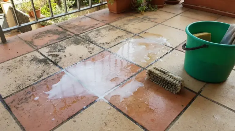 Piastrelle del balcone parzialmente pulite con spazzola, secchio e soluzione detergente
